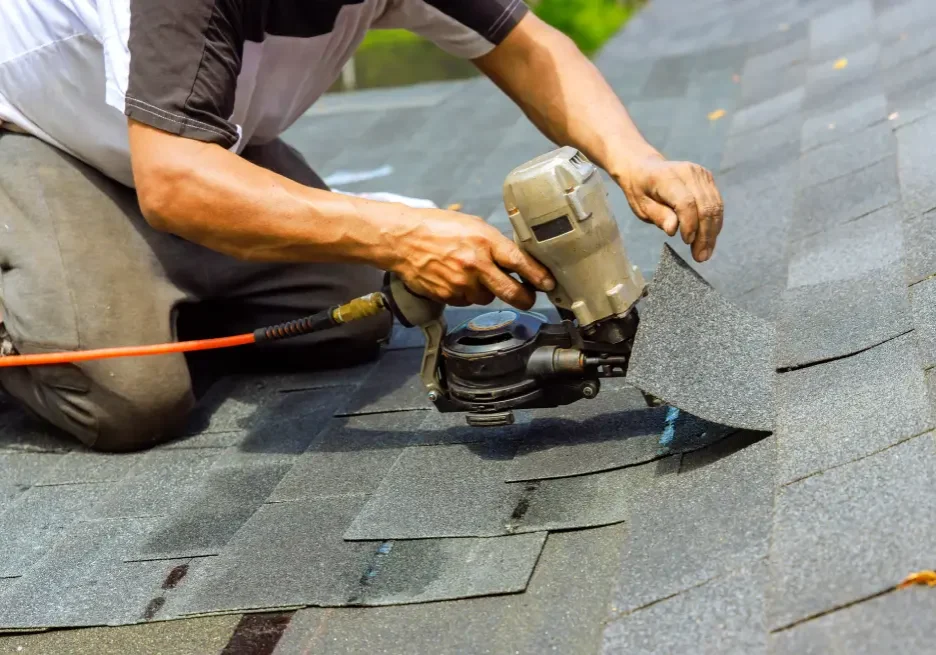 Worker installing asphalt shingles on roof.